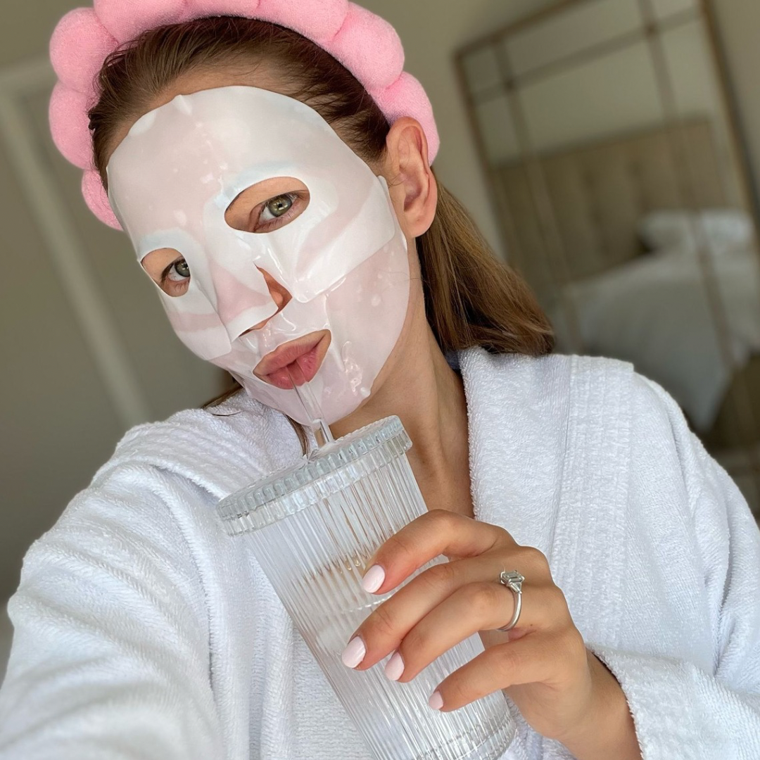 Woman wearing a LunèBevra facial sheet mask and a pink headband
